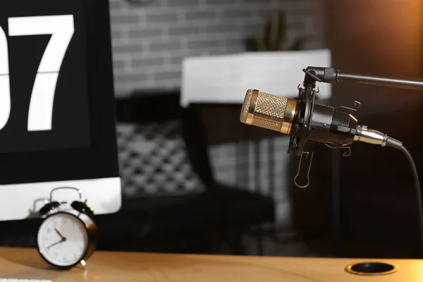 Stand with professional microphone near workplace in dark room