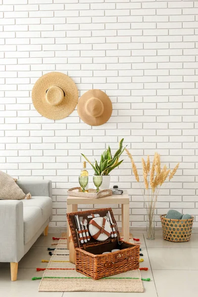 Salondaki halının üstünde piknik için bulaşık sepetinin olduğu sepet.