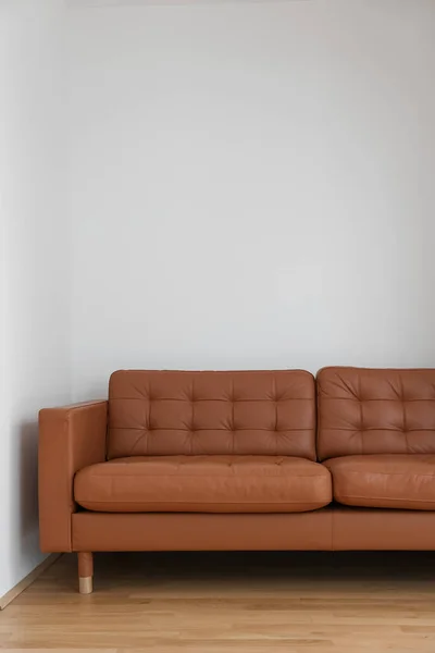 Brown couch near light wall in room