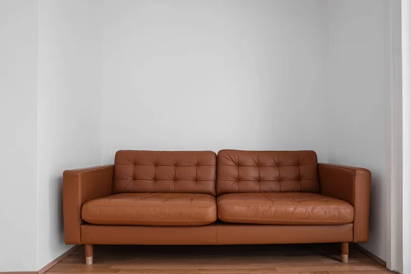 Brown leather couch near light wall in room