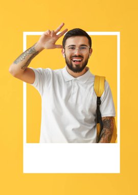 Yakışıklı, dövmeli erkek öğrenci. Sarı arka planda çerçeveden dışarı bakıyor.