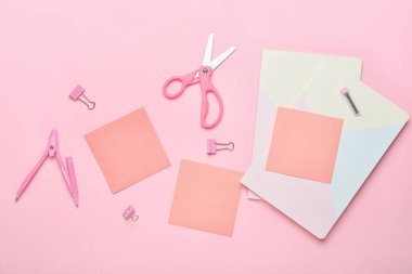 Pembe arka planda yapışkan notlar, defterler ve ofis malzemeleri.