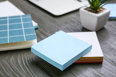 Gri ahşap masadaki boş yapışkan notlar yığını, yakın çekim