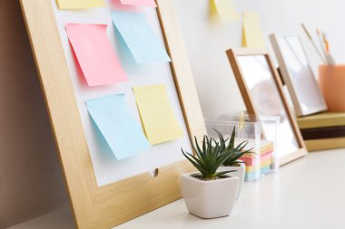 Different blank sticky notes and houseplants on white table, closeup