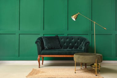 Yeşil duvarın yanında şık bir kanepe ve modern lamba