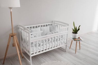 Bebek beşiği, lamba ve masayla aydınlatma odasının içinde.