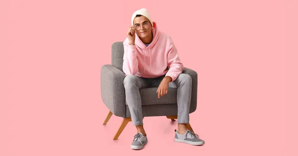 Przystojny Młody Człowiek Siedzi Miękkim Fotelu Różowym Tle — Zdjęcie stockowe