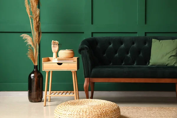 Yeşil duvarın yanında şık bir kanepe, puf ve masa.