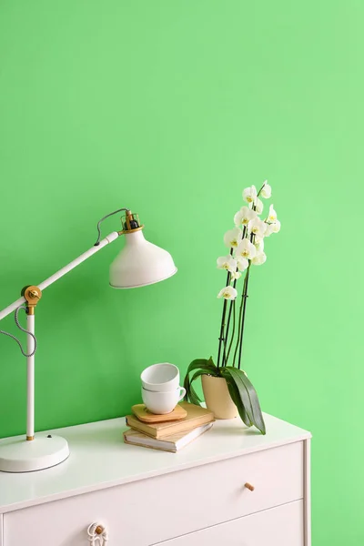 Lamp Cups Books Beautiful Orchid Flower Chest Drawers Green Wall — Stock fotografie