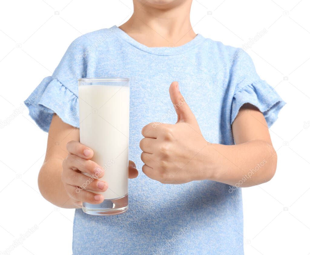 Little girl holding glass of milk and showing thumb up on white background, closeup