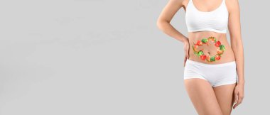 Gri arka planda sağlıklı ürünleri olan genç bir kadın. Diyet kavramı