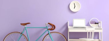 Modern dizüstü bilgisayarı ve leylak duvarının yanında bisikleti olan işyeri