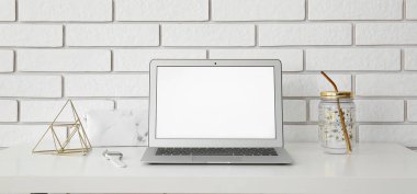 Beyaz tuğla duvarın yanında modern dizüstü bilgisayarı olan bir işyeri