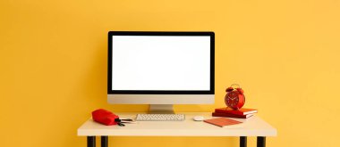 Sarı duvarın yanında modern bilgisayar ve kırtasiye malzemesi olan işyeri