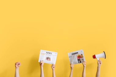 Sarı arka planda gazeteleri ve megafonu olan insanlar.
