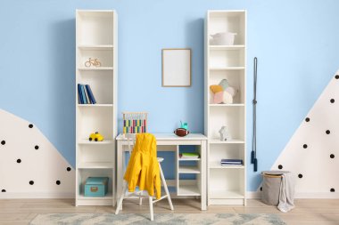 Çocuk odasındaki renkli duvarın yanında oyuncakları olan rugby topu ve raf üniteli bir masa.