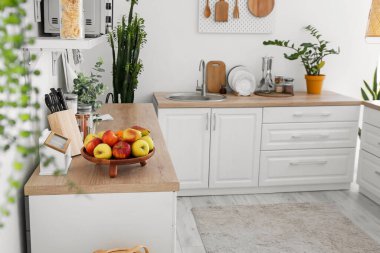 Wooden tray with fruits on counter in kitchen interior