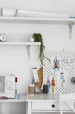 Işık duvarının yanında dikiş makinesi ve tahta olan Atıcı