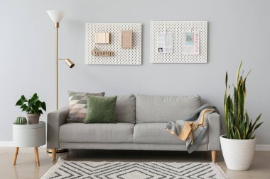 Rahat kanepesi, çiçekleri ve gri duvarları olan modern oturma odasının içinde.