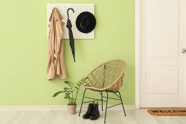 Interior of stylish hallway with armchair and pegboard near color wall