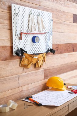 Tahtada farklı aletler ve atölyede ahşap duvarın yanında masa var.