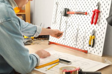 Atölyedeki aletlerle panodan anahtarı alan adam