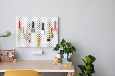 Aletler, lamba ve ışık duvarının yanındaki bitkilerle rahat bir dekoratör işyeri.