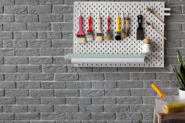 Gri tuğla duvarda dekoratör aletleri olan tahta.