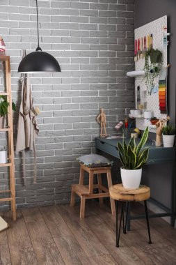 Oda içindeki gri tuğla duvarın yanındaki modern dekoratörün işyeri.