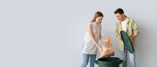Junges Paar Legt Müll Mülleimer Auf Hellem Hintergrund Mit Platz — Stockfoto