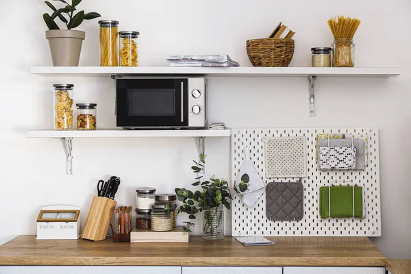 Modern kitchen with counter, shelves and pegboard near light wall