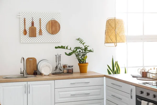 浅色厨房 有时尚的柜台 厨房用具和白墙上的踏板 — 图库照片
