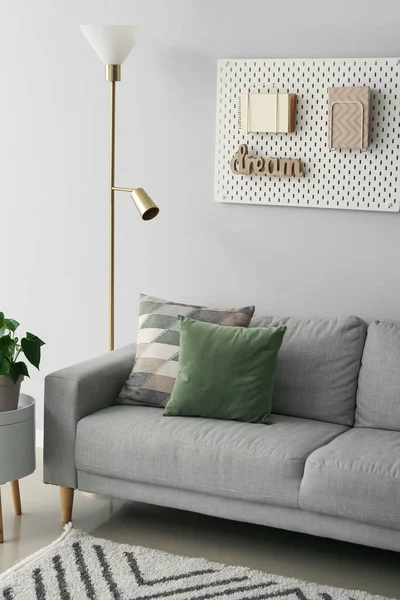 Rahat bir kanepe, zemin lambası ve oturma odasındaki gri duvarda tahta.