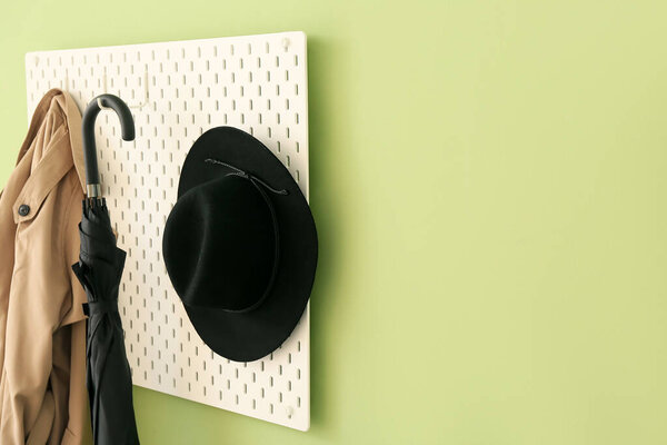 Pegboard with clothes and accessories on color wall
