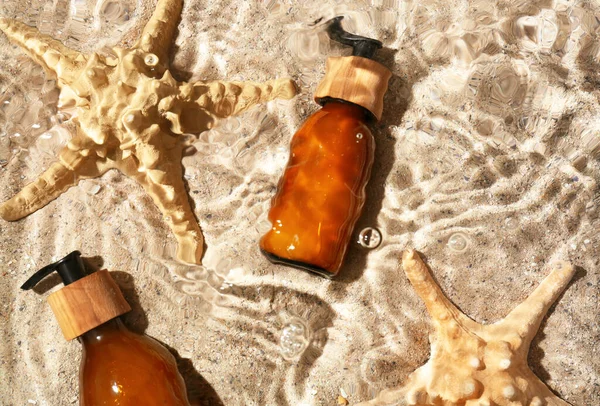 Dispenser Bottles Cosmetic Product Starfishes Water Sand Background — стоковое фото