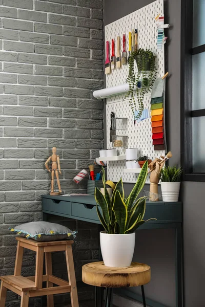Gri tuğla duvarın yanında tahta ve modern aletlerle dekoratörün işyeri