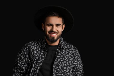 Siyah arka planda şık şapkalı, modaya uygun sakallı adam.