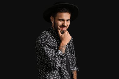 Siyah arka planda modaya uygun sakallı bir adam.