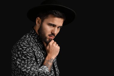 Karanlık arka planda düşünceli sakallı bir adamın portresi.