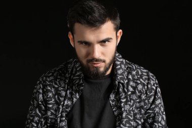 Karanlık arka planda sakallı bir adamın portresi.