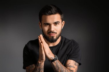 Koyu arkaplanda şık kol saati olan sakallı bir adam.