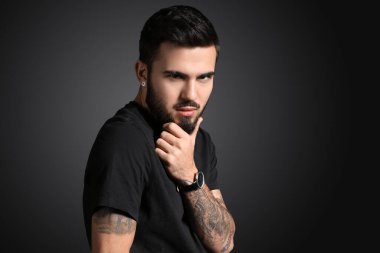 Koyu arkaplanda sakala dokunan şık bir adam.