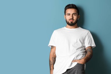 Mavi arka planda poz veren modaya uygun sakallı adam.