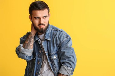 Modaya uygun sakallı adam sarı arka plana bakıyor.