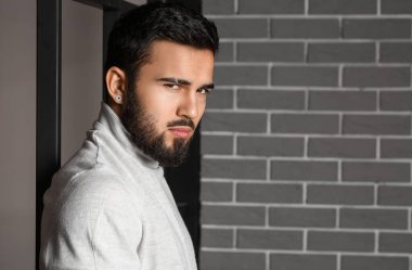 Gri tuğla duvarın yanında modaya uygun sakallı adam.