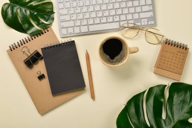 Modern klavye, not defterleri, bir fincan kahve ve sarı arka planda tropikal yapraklar.