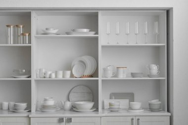 Loş duvarın yanında yemek takımı olan raf ünitesi.