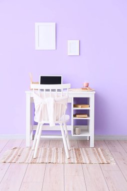 Diz üstü bilgisayarı ve duvarında boş çerçeveleri olan işyeri