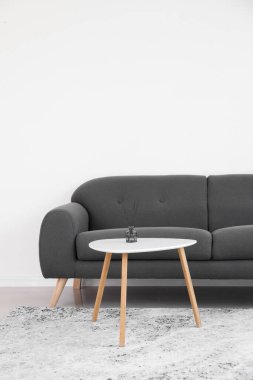 Table with reed diffuser and black sofa near light wall