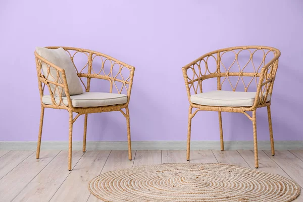 Wicker chairs near violet wall in room interior